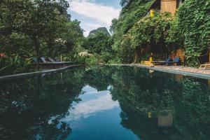 a swimming pool with a reflection of the sky in the water at Trang An Ecolodge in Ninh Binh