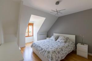 um quarto branco com uma cama e uma ventoinha de tecto em La Petite Chalautrière - Avec grand jardin 