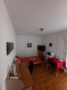 Sala de estar con cama roja y mesa en Chambre SOLO Toulon Ouest, en Toulon