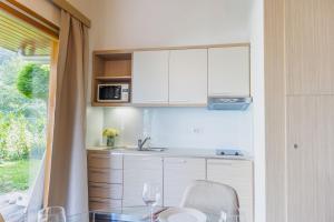 a kitchen with white cabinets and a glass table at Apartment Rosemary in Topolšica