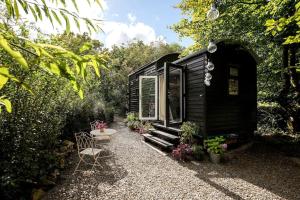 a black tiny house with a bench and a table at Fleur de Grog - Shepherds Hut in Bodmin