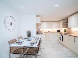 a white kitchen with a table and chairs in it at Stylish Spacious 1 Bedroom Apt At Dealhouse in Huddersfield