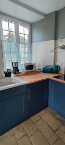 una cucina con armadi blu e piano di lavoro di Loge de la Saire a Gonneville