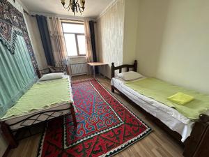 a room with two beds and a rug at Kurak Homestay in Bishkek