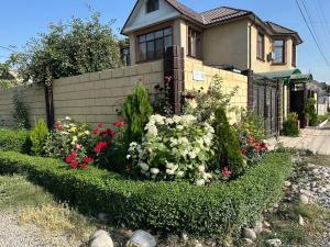 a house with a garden of flowers in front of it at Kurak Homestay in Bishkek