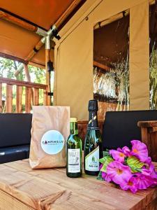 zwei Flaschen Wein auf einem Tisch mit Blumen in der Unterkunft Safari Tent M in Berdorf