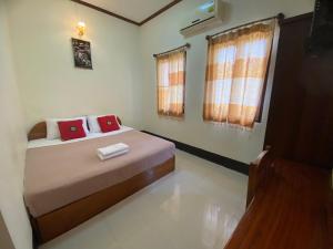 a bedroom with a bed with two red pillows at A Tee Guesthouse in Luang Prabang