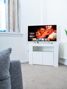 a tv sitting on a white stand in a living room at Stylish Spacious 1 Bedroom Apt At Dealhouse in Huddersfield