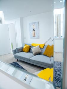 a living room with a blue couch with yellow pillows at Stylish Spacious 1 Bedroom Apt At Dealhouse in Huddersfield