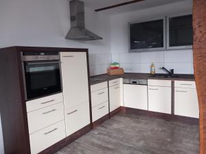 uma cozinha com armários brancos e um forno com placa de fogão em Ferienwohnung 1 Bartölke em Bockenem