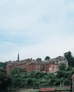 a large red brick building on a hill with a church at La Merveilleuse by Infiniti Resorts in Dinant