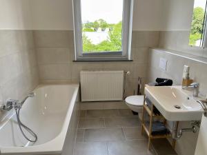 a bathroom with a tub and a toilet and a sink at FLATLIGHT - Stylish apartment - Kitchen - Parking - Netflix in Hildesheim