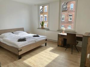 a bedroom with a bed and a desk and two windows at FLATLIGHT - Stylish apartment - Kitchen - Parking - Netflix in Hildesheim