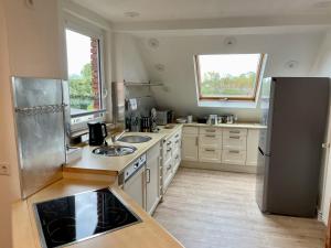 uma cozinha com armários brancos e um frigorífico de aço inoxidável em FLATLIGHT - Stylish apartment - Kitchen - Parking - Netflix em Hildesheim