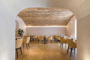 uma sala de jantar com mesas e cadeiras e um tecto de tijolos em Palazzo Artemide - VRetreats em Siracusa