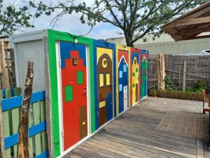 a row of colorful doors on a wooden boardwalk at Stoke Travel's Amsterdam Camping in Amsterdam