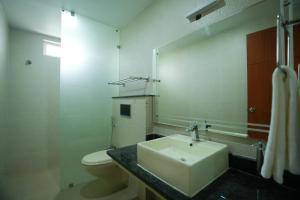 un bagno con lavandino, water e specchio di Urban Suites a Bhubaneshwar
