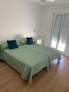 een groot groen bed met blauwe kussens in een slaapkamer bij Fariñas 15 in Sanlúcar de Barrameda