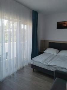 Domki Bałtycka 14a في جيبوفو: غرفة نوم بسرير مع ستائر بيضاء