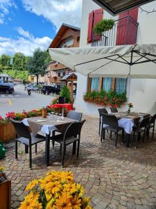 un patio con mesas, sillas y una sombrilla en Al Sole Hotel Ristorante dal 1870 en Pieve di Cadore