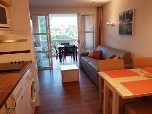 a living room with a couch and a kitchen with a table at Cap Esterel Village : studio 4 pers au calme climatisé F5 in Agay - Saint Raphael