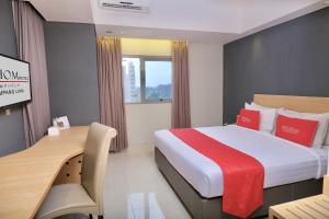 スマランにある@Hom Semarang Simpang Limaの大きなベッドとデスクが備わるホテルルームです。