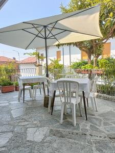2 mesas y sillas con sombrilla en el patio en Affittacamere San Rocco en Aramengo