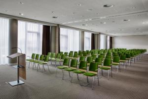 una sala de conferencias con sillas verdes y un podio en IntercityHotel Heidelberg en Heidelberg