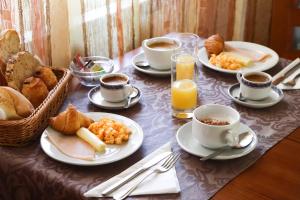a table with plates of breakfast foods and cups of coffee at Hotel Louro in Óbidos