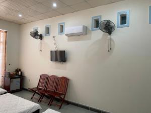 um quarto com duas cadeiras e uma ventoinha na parede em Hotel Cát Tường em La Gi