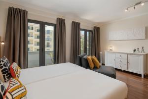 a bedroom with a white bed and a large window at Apartamento na Praça by An Island Apart in Funchal
