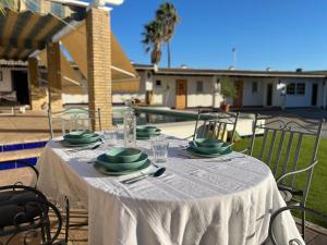 una mesa con un mantel blanco y platos verdes. en El Patio de las Minas, en Aznalcázar