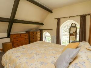 a bedroom with a bed and a dresser and a window at St Marks School House in Llanwrthwl
