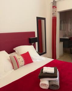Un dormitorio con una cama roja y blanca con toallas. en Logis Hotel Restaurant Le Domaine de la Régalière en Anduze