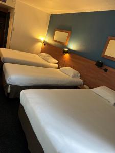 three beds in a hotel room with lights on the wall at Kyriad Marne-La-Vallée Torcy in Torcy