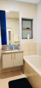 a bathroom with a tub and a sink and a mirror at 2 bedrooms apartment in Johannesburg