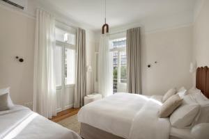 a white bedroom with two beds and a window at Loft in Acropolis in Athens