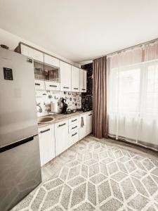 a kitchen with white cabinets and a refrigerator at Apartament One Divine - Zarnesti in Zărneşti