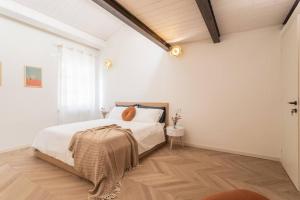 una camera bianca con letto e pavimento in legno di Luxury & Design: Oasi nel centro storico di Rimini a Rimini