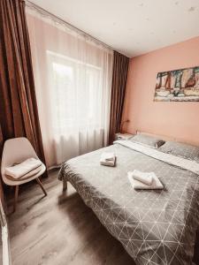 a bedroom with a bed and a chair and a window at Apartament One Divine - Zarnesti in Zărneşti