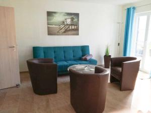 ein Wohnzimmer mit einem blauen Sofa und Stühlen in der Unterkunft Ferienhaus Poseidon in Altefähr