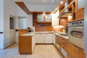 a kitchen with white counters and wooden cabinets at City Apartment With Garden - Happy Rentals in Rijeka