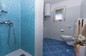 baño de azulejos azules con ducha y aseo en Apartments Toma, en Kaštela