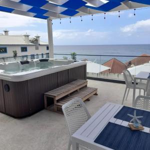 a hot tub on a patio with a table and chairs at Mediterrâneo Madeira in São Vicente