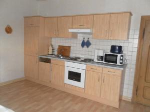 eine Küche mit Holzschränken, einem Herd und einer Mikrowelle in der Unterkunft Two separate farmhouse apartments under one roof in Trendelburg