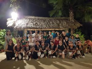 um grupo de pessoas posando para uma foto em frente a uma cabana em Vu Linh Palm House Homestay - Bungalow em Yen Bai