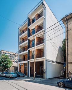 un edificio alto con coches estacionados frente a él en Vato Home en Tiflis