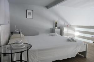 a white bedroom with a bed and a glass table at Carega City Center Apartment in Verona