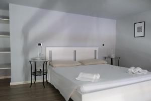 a white bedroom with a white bed and two tables at Carega City Center Apartment in Verona