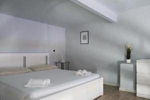 a white bedroom with a white bed with two towels at Carega City Center Apartment in Verona